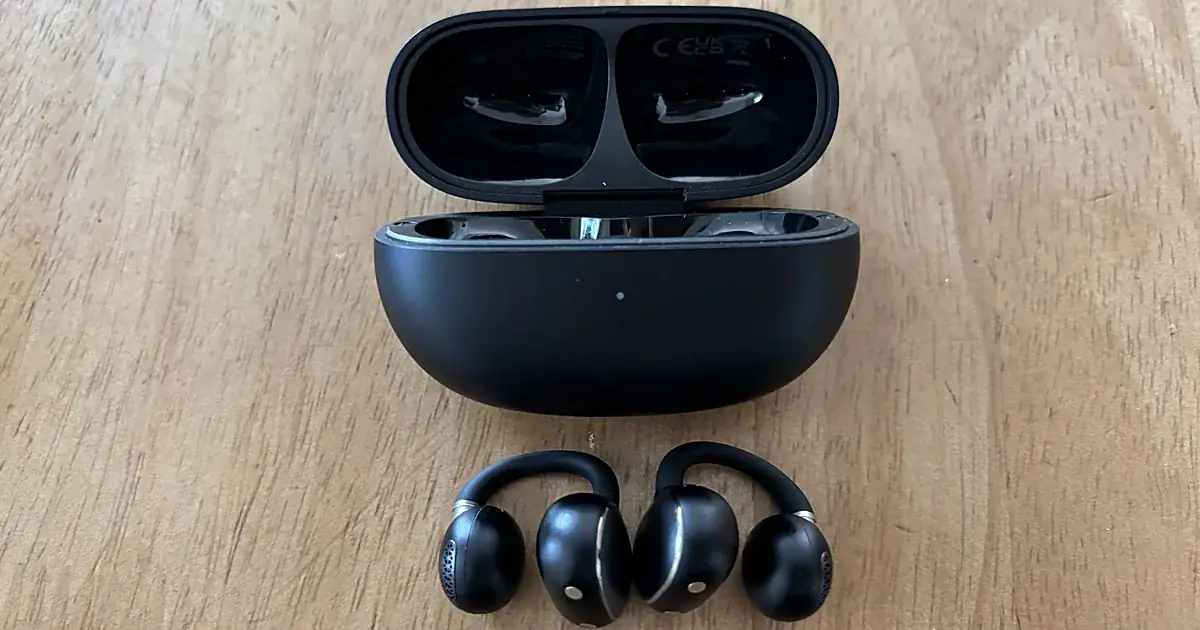EarFun Clip 2の本体2つと、ふたを開けた充電ケースを木のテーブルに並べた写真